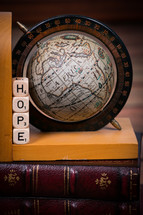A globe bookend and dice spelling "hope" on a leather Bible.