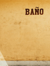 A stucco wall with the word "bano."