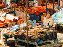 woman selling spices and vegetables in a market 
