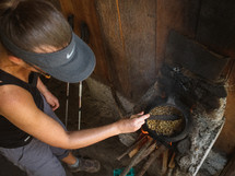 A woman cooks beans over a wood burning stove.