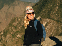female hiker with a backpack, cap, and sunglasses 