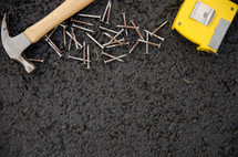 hammer, nails, and tape measure on asphalt