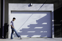 Boy standing outside closed garage door with foot on soccer ball.