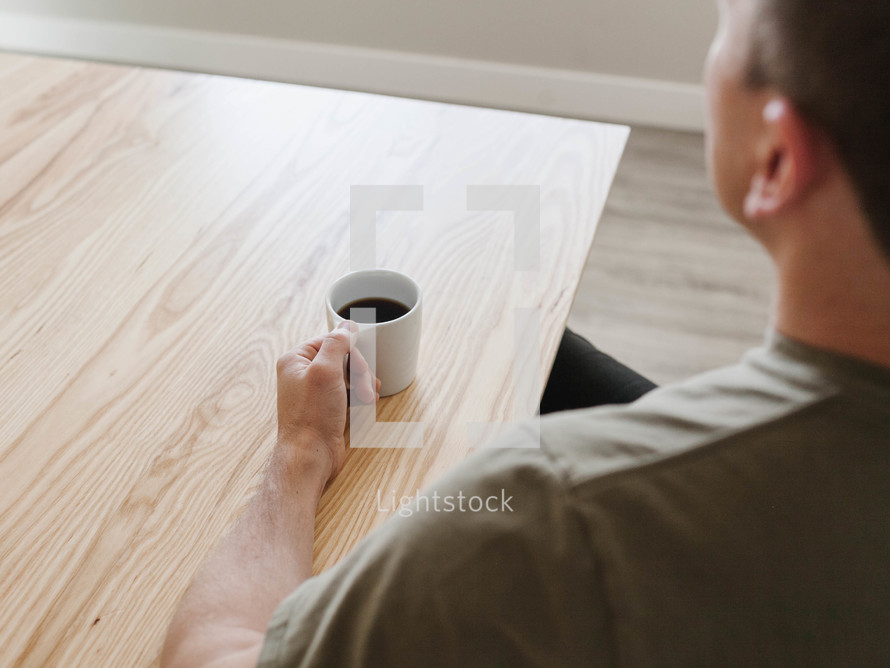 a man sitting with a mug of coffee 