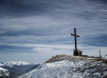 cross at the top of a snow covered mountaintop 