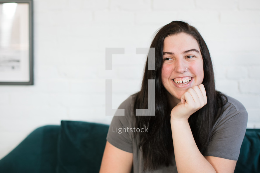 a smiling young woman sitting on a couch 