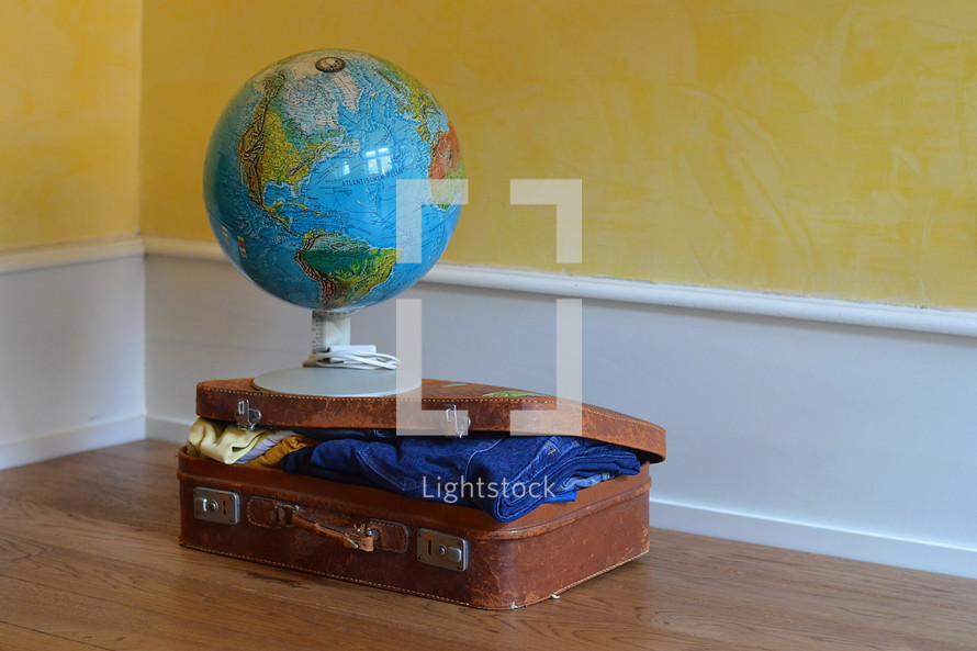 a globe on a packed suitcase 