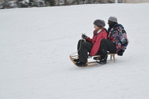 laughing couple sledding together