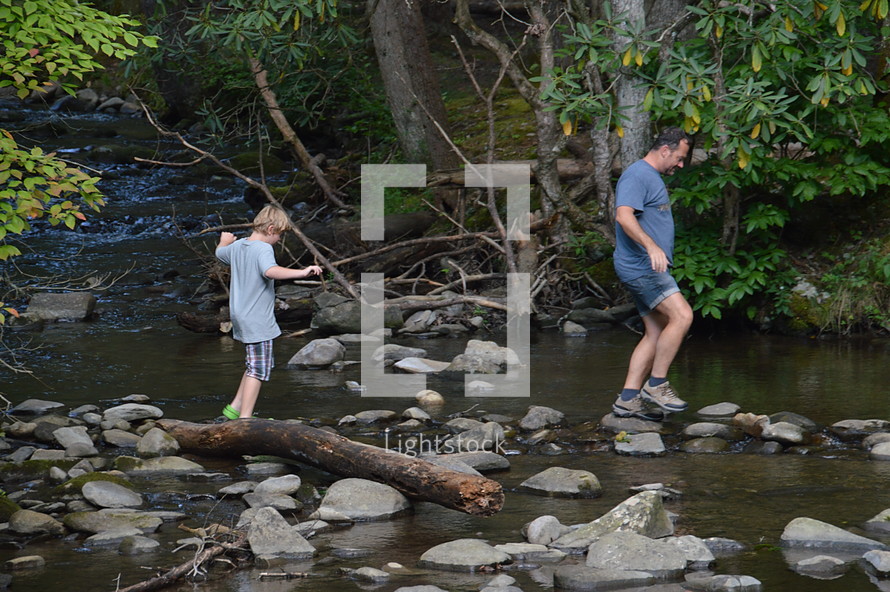 father and son exploring a creek
