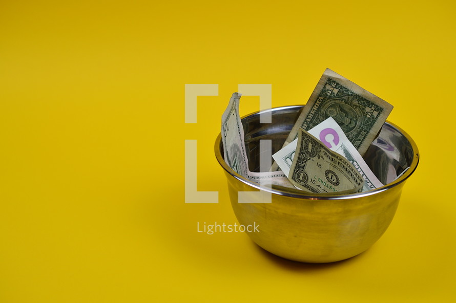 dollar bills in a bowl on a yellow background 
