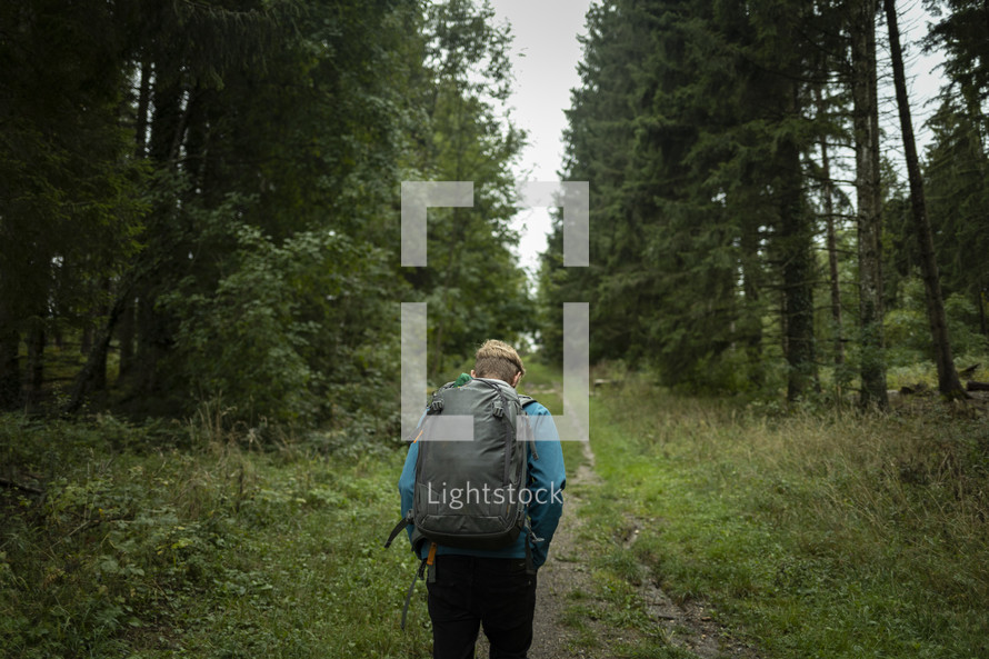Man with backpack hiking through forest path