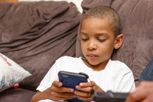 A boy playing a video game on a couch.