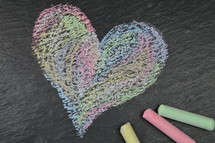 heart shape in sidewalk chalk on slate with chalk sticks 