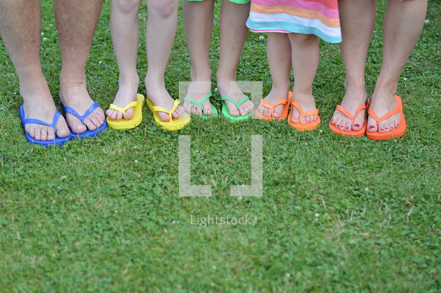 feet in colorful flip flops standing in the grass 