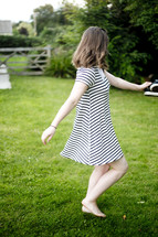 a woman twirling in the grass barefoot 