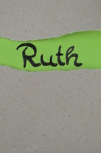torn open kraft paper over green paper with the name of the book Ruth