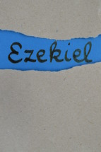 Ezekiel - torn open kraft paper over blue paper with the name of the prophetic book  Ezekiel