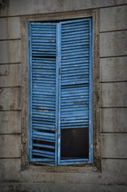 broken blue shutters in a window 