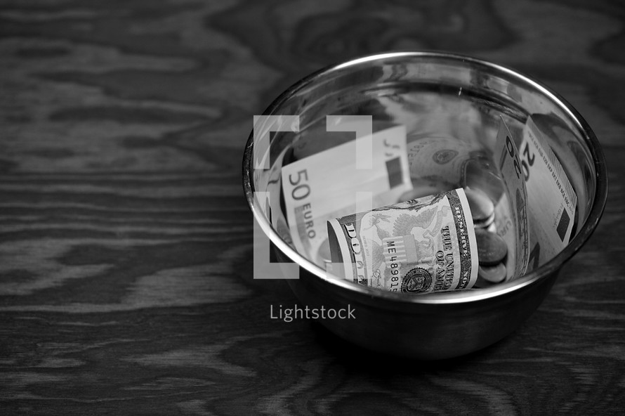various currency in a bowl on a wood background 