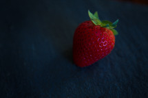 a single strawberry on blue 