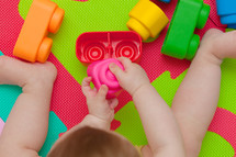 toddler plays with building block on the colored rubber mat