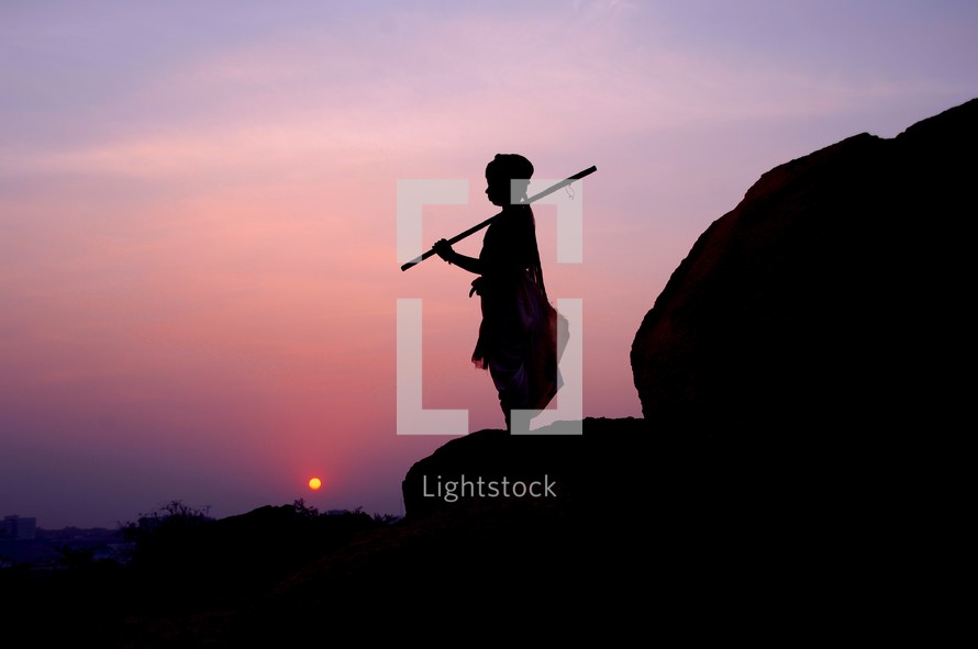 silhouette of a boy holding a stick at sunset 