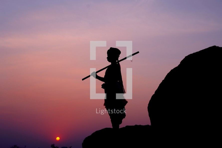 silhouette of a shepherd boy holding a walking stick 