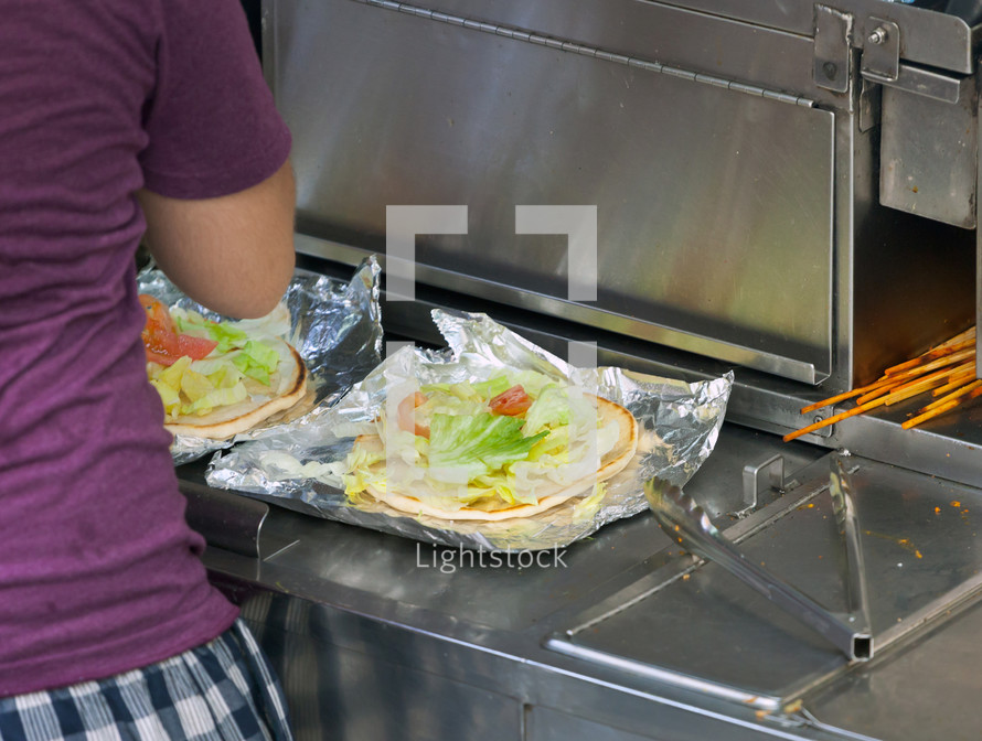 Street food vendor prepares a flat bread with salad and other ingredients. New York City, USA.
