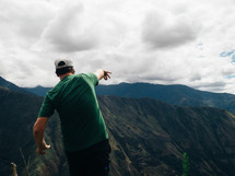 A man throws a rock from a mountaintop.