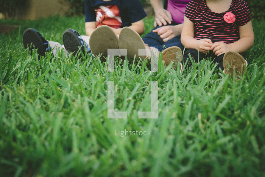 Mother, daughter, and son's feet in grass