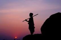 silhouette of a shepherd boy holding a walking stick 