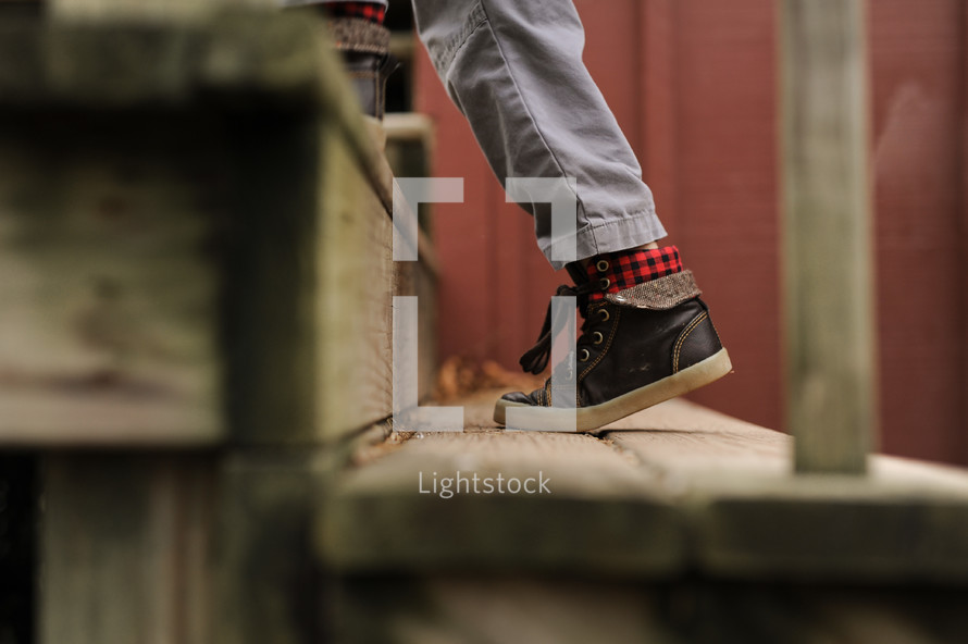 legs of a boy child on wooden steps outdoors 