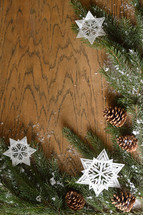 star ornaments, pine cones, snow, and pine boughs on a wooden  background 