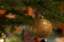 gold glittery ornament hanging from a Christmas tree 