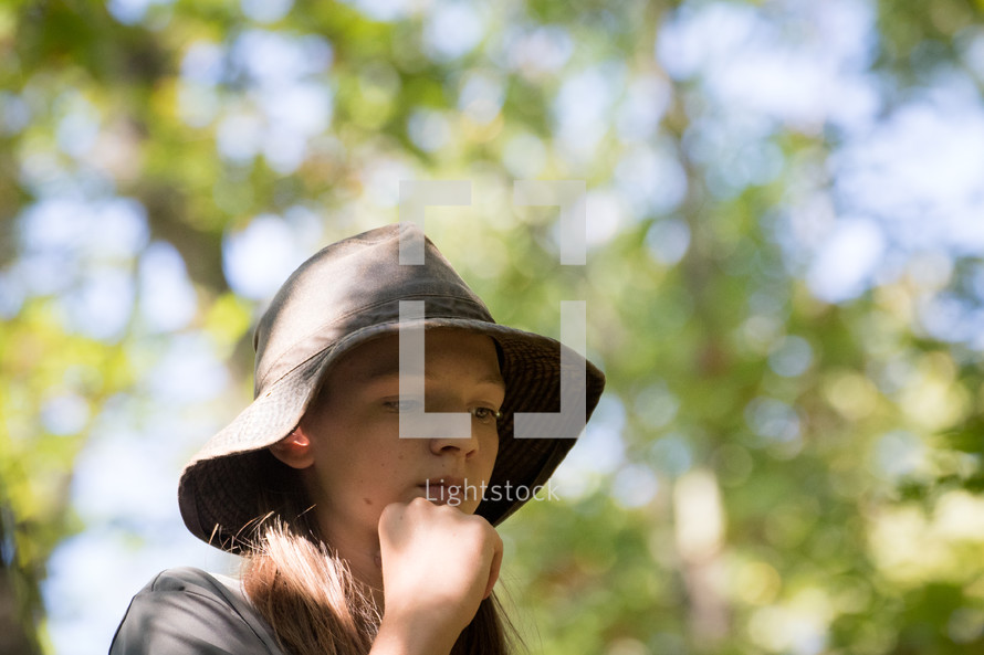 teen girl in a hat standing in a forest 