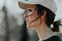side profile of a woman in a ball cap and ponytail 