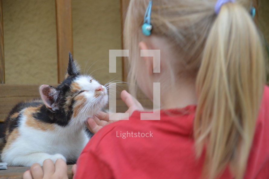 a little girl petting a cat 