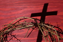 crown of thorns with shadows on a red wooden background