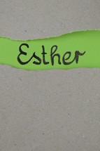 torn open kraft paper over green paper with the name of the book Esther