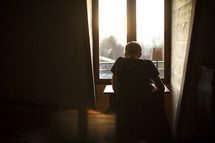 young man sitting at a desk in a window 