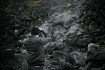 a man stopping to take a picture of a rocks mountainside 