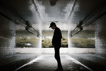 a man standing in a dark urban tunnel 