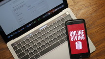 cellphone with online giving app on a laptop computer 
