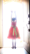 a girl child standing in sunlight from an open doorway 
