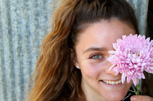 smiling woman holding a pink flower 