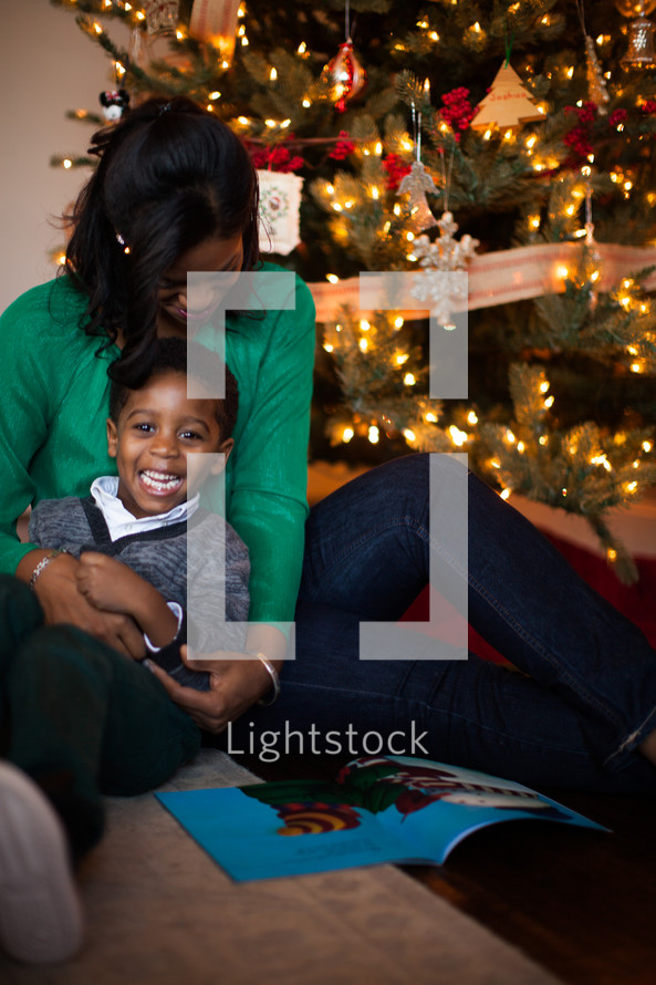 mother and son reading a book near a Christmas tree 