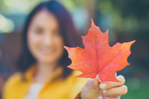 a woman holding a fall leaf