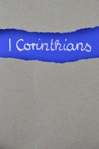 1 Corinthians - torn open kraft paper over intense blue paper with the name of the first letter from Paul to the Corinthians