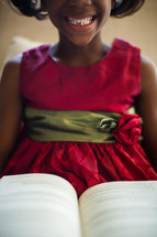 a girl child in pigtails reading a Bible 