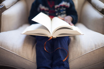 boy child reading a Bible on a couch 